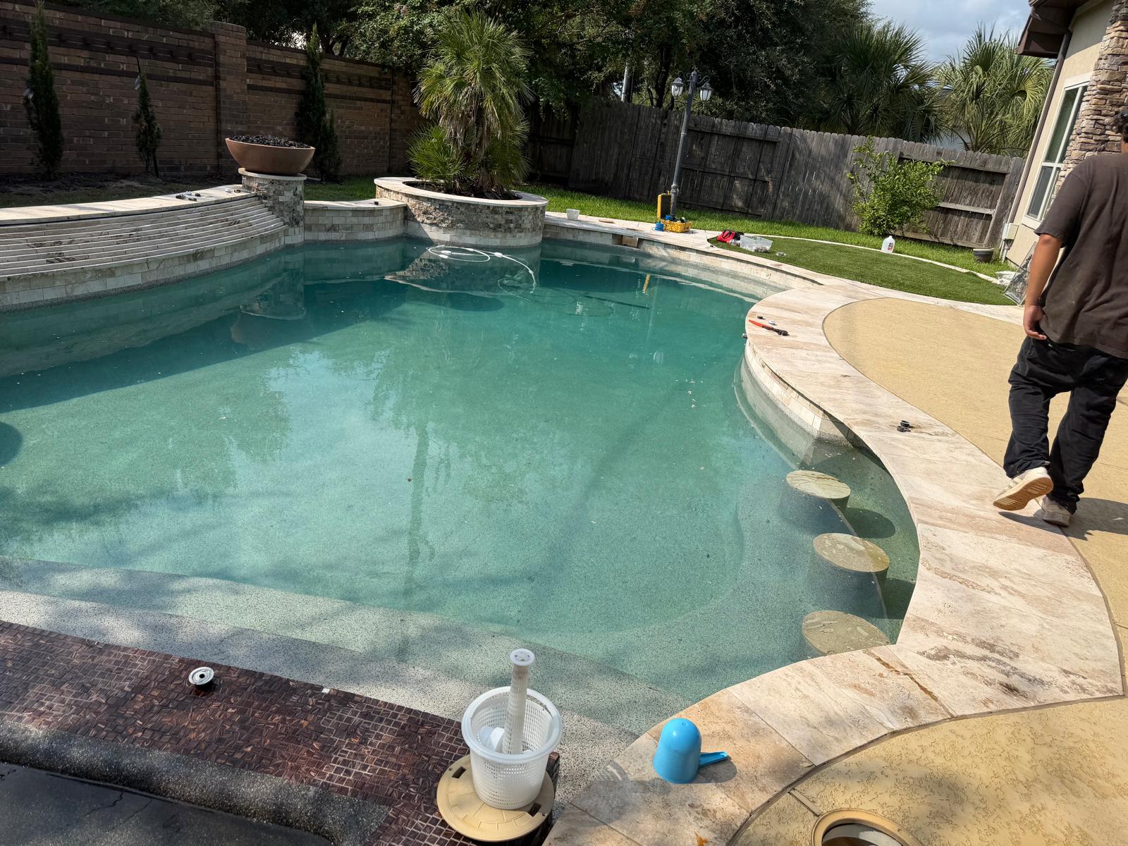 Custom luxury residential pool with swim-up bar stools and travertine coping built by Dynamo Pools in Katy Texas